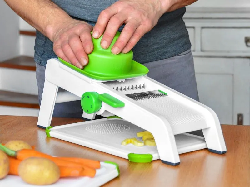 mandolina verde e bianca che taglia verdura a julienne